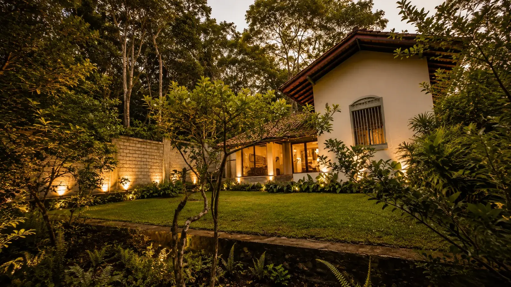 Villa Two's exterior viewed through the surrounding garden at dusk