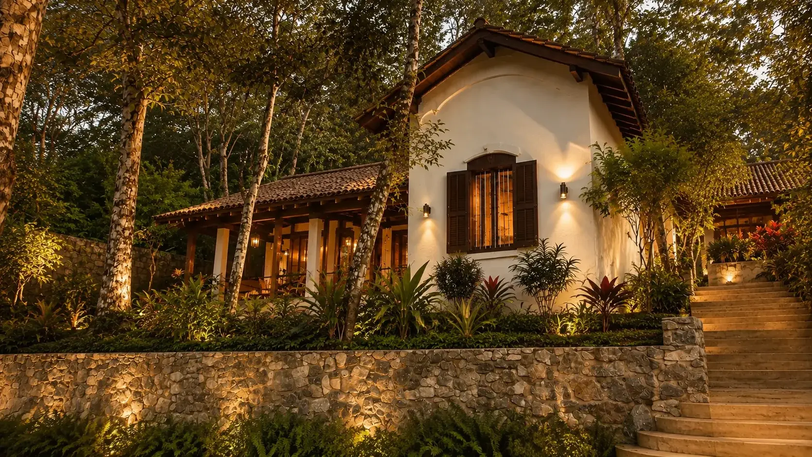 Villa One's colonial exterior lit at dusk, seen through the plantation trees